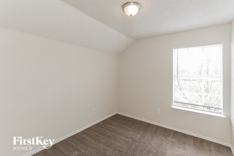 a bedroom with white walls and a window and a brown carpet