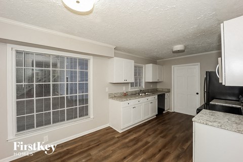 A kitchen with white cabinets and a wooden floor.