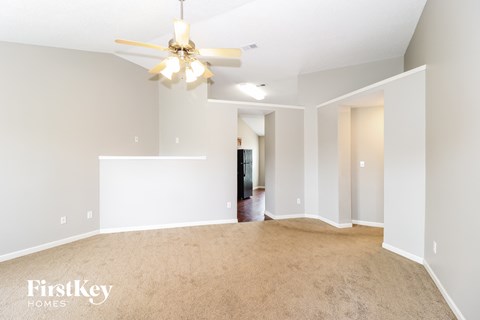 a spacious living room with carpet and a ceiling fan