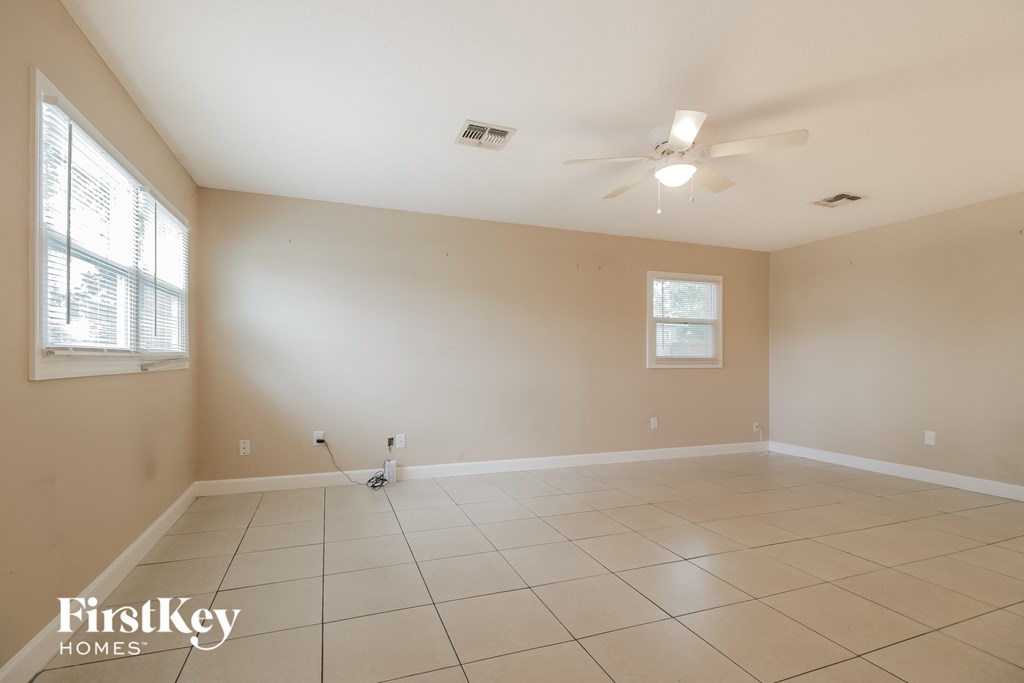 an empty living room with a ceiling fan and a tiled floor