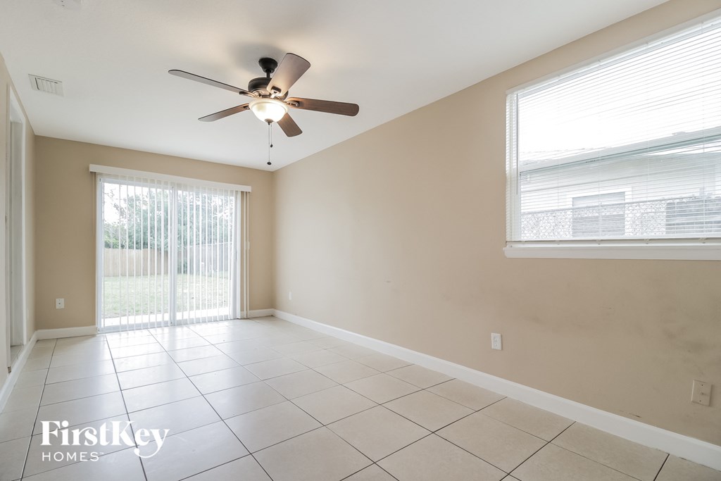 an empty living room with a ceiling fan and a window