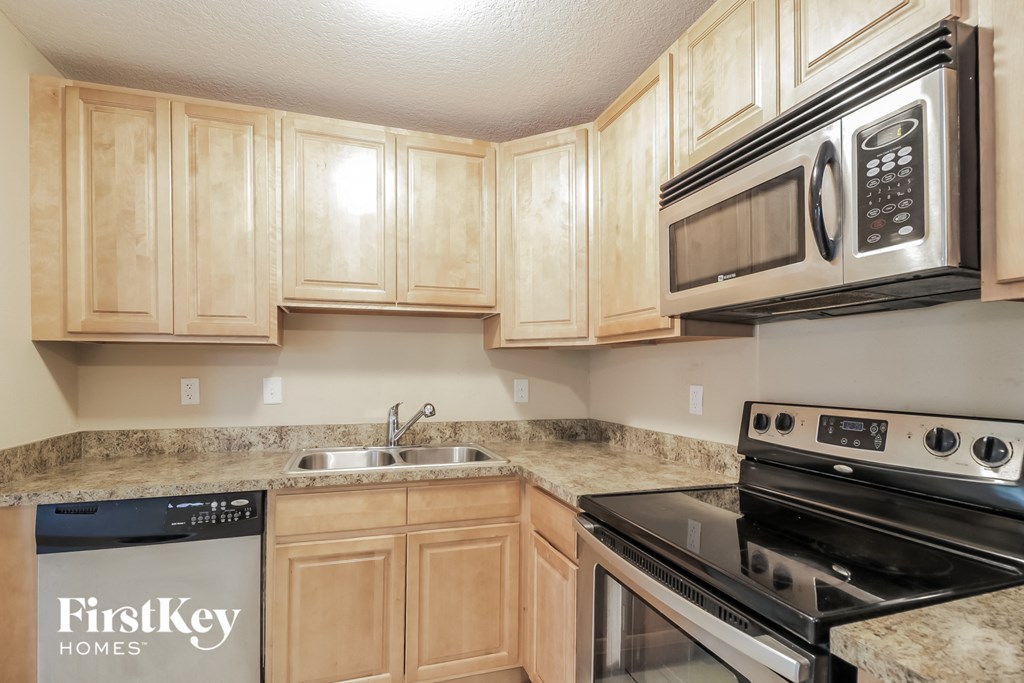 a kitchen with wood cabinets and a stove microwave and sink