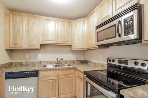 a kitchen with wood cabinets and a stove microwave and sink