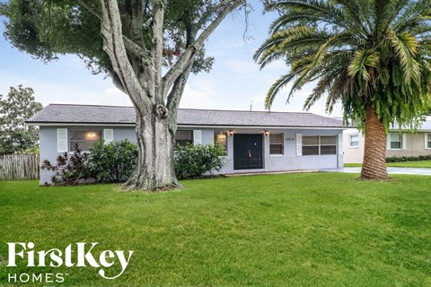 a white house with a lawn and palm trees