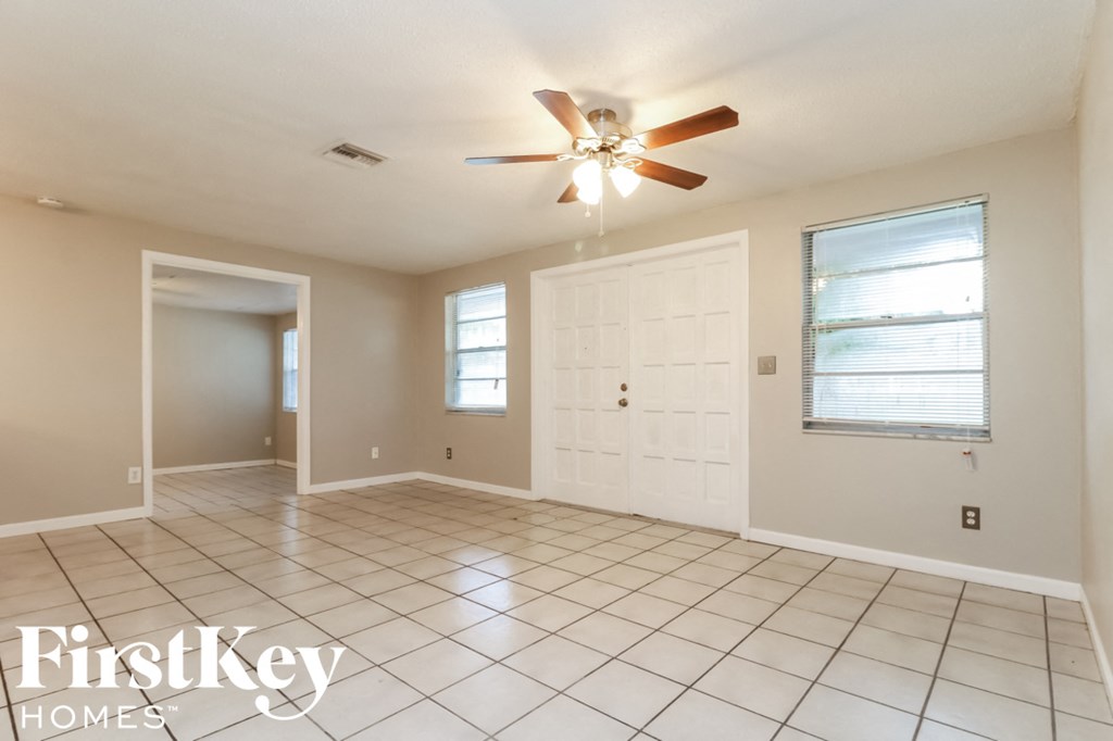 a clean and empty living room with a ceiling fan