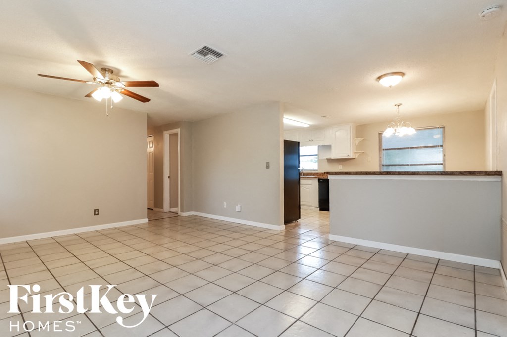 an empty living room and kitchen with a ceiling fan