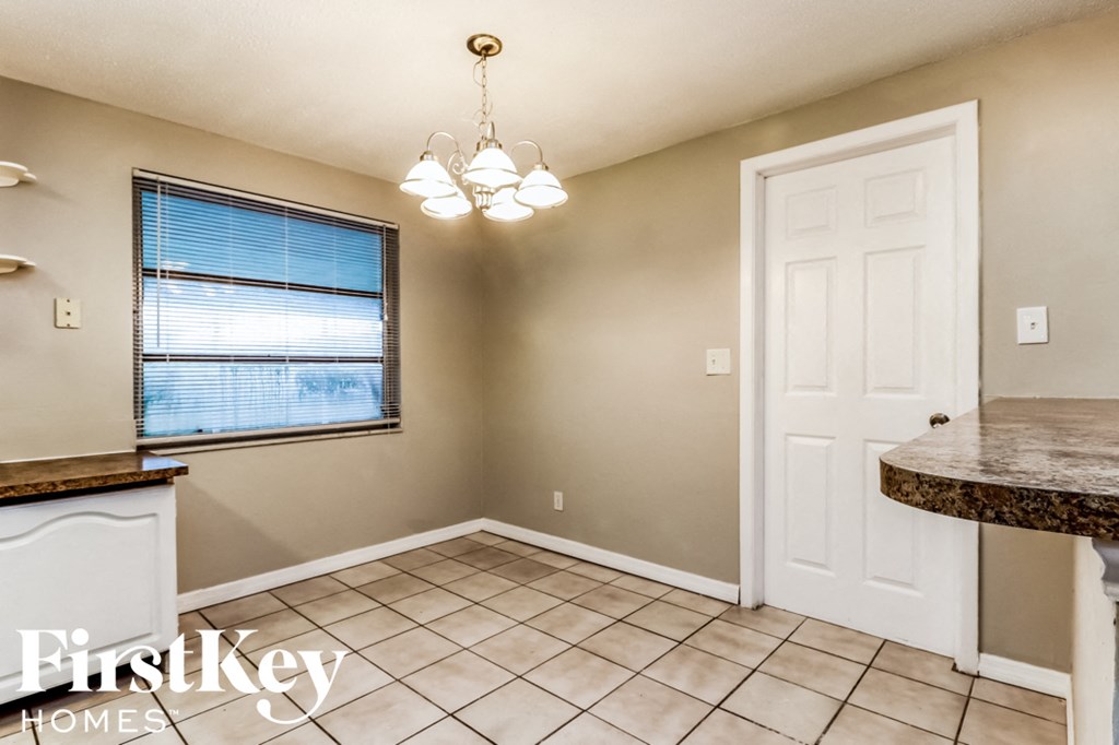 an empty kitchen and dining room with tile flooring and a window