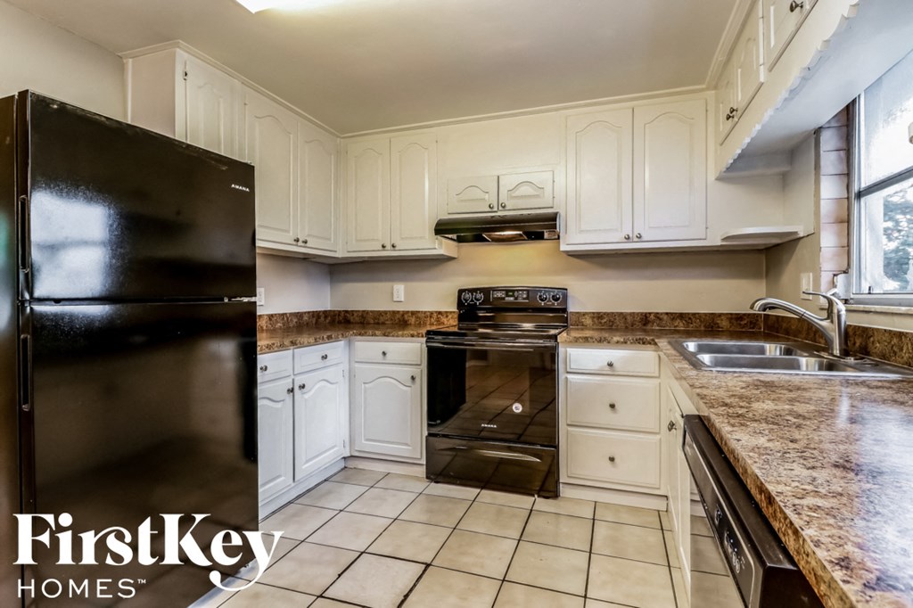 a kitchen with white cabinets and a black refrigerator