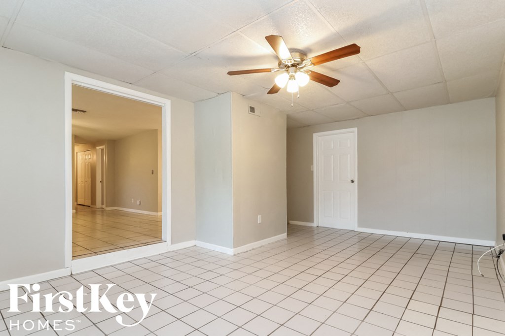 an empty living room with a ceiling fan and a white tile floor