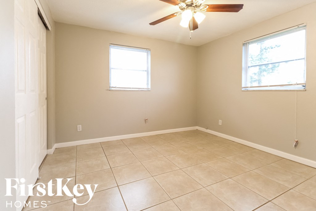 a empty room with a ceiling fan and two windows