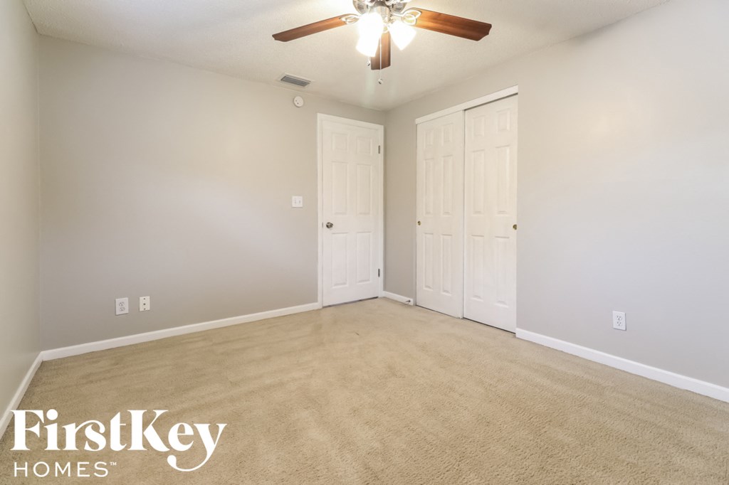 an empty living room with two doors and a ceiling fan