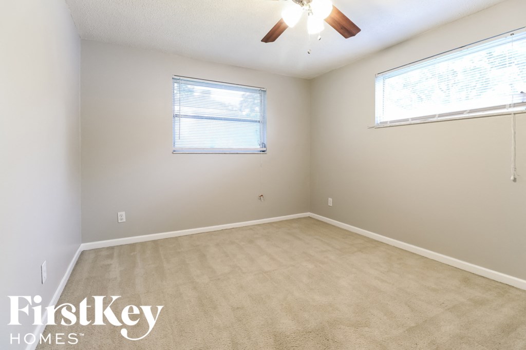 an empty room with a ceiling fan and two windows