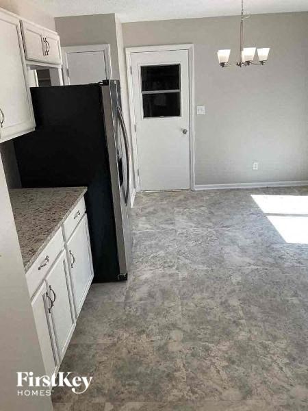 a kitchen with white cabinets and a black refrigerator