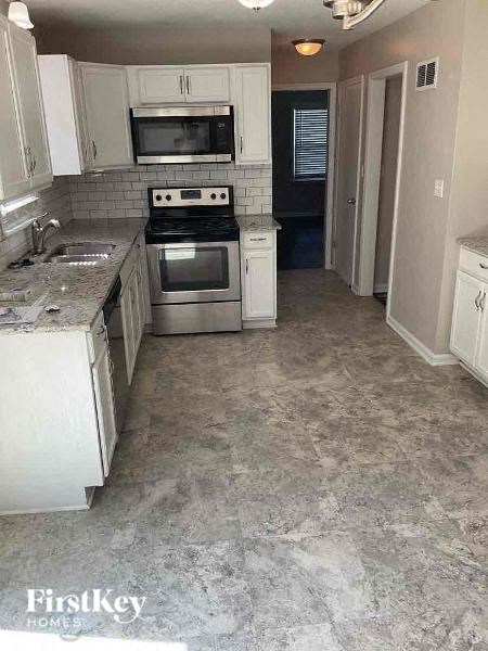 a kitchen with white cabinets and a stove and a sink