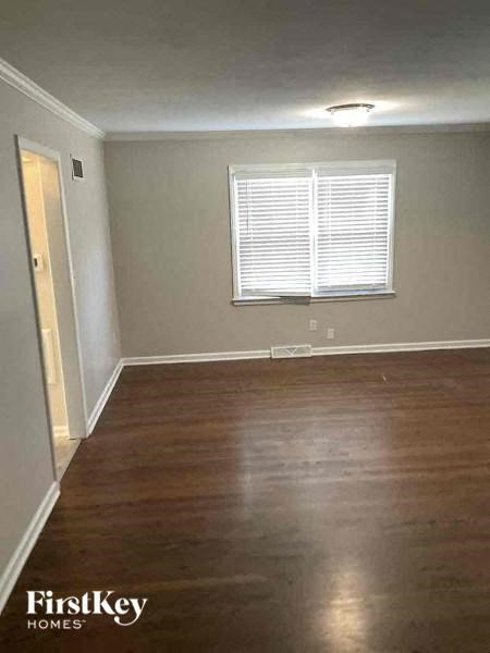 an empty living room with wood floors and a window