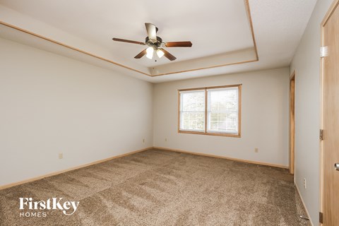 a living room with carpet and a ceiling fan