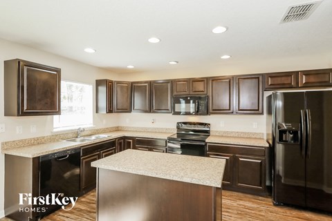 A kitchen with dark wood cabinets and a black refrigerator.