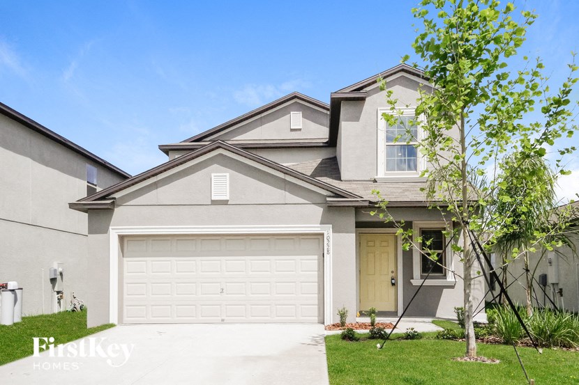 A two-story house with a garage and a tree in front.
