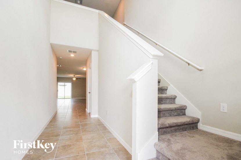 A staircase with a beige carpeted runner and white risers.
