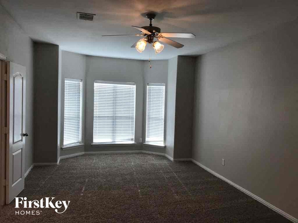 an empty room with a ceiling fan and three windows