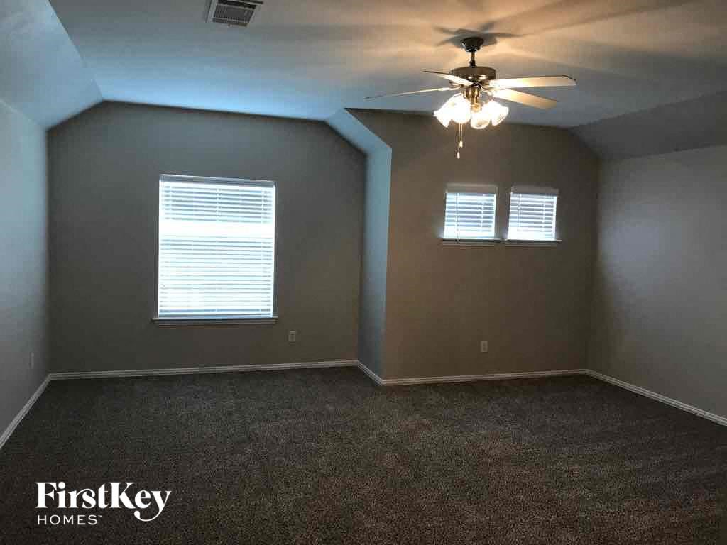 an empty room with a ceiling fan and two windows