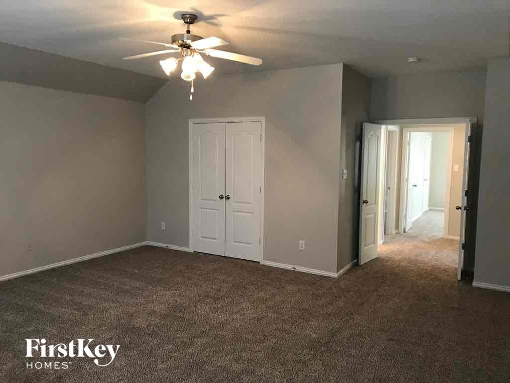 an empty living room with a ceiling fan and a door to a closet