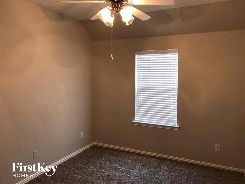 an empty bedroom with a ceiling fan and a window