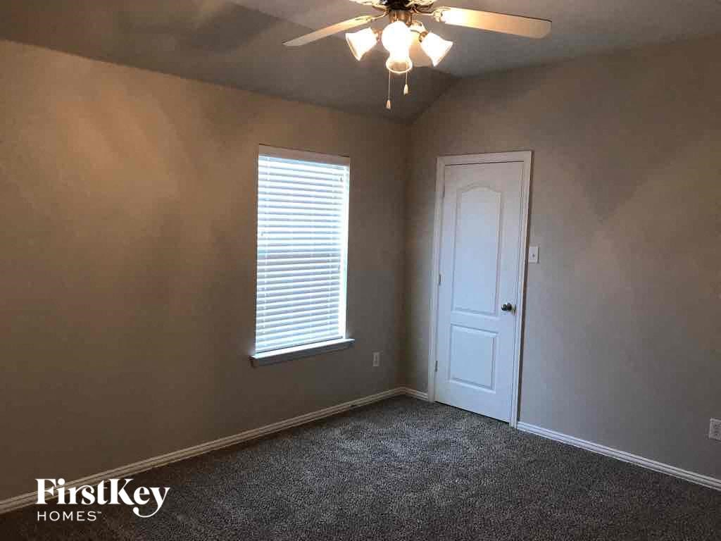 an empty bedroom with a white door and a ceiling fan
