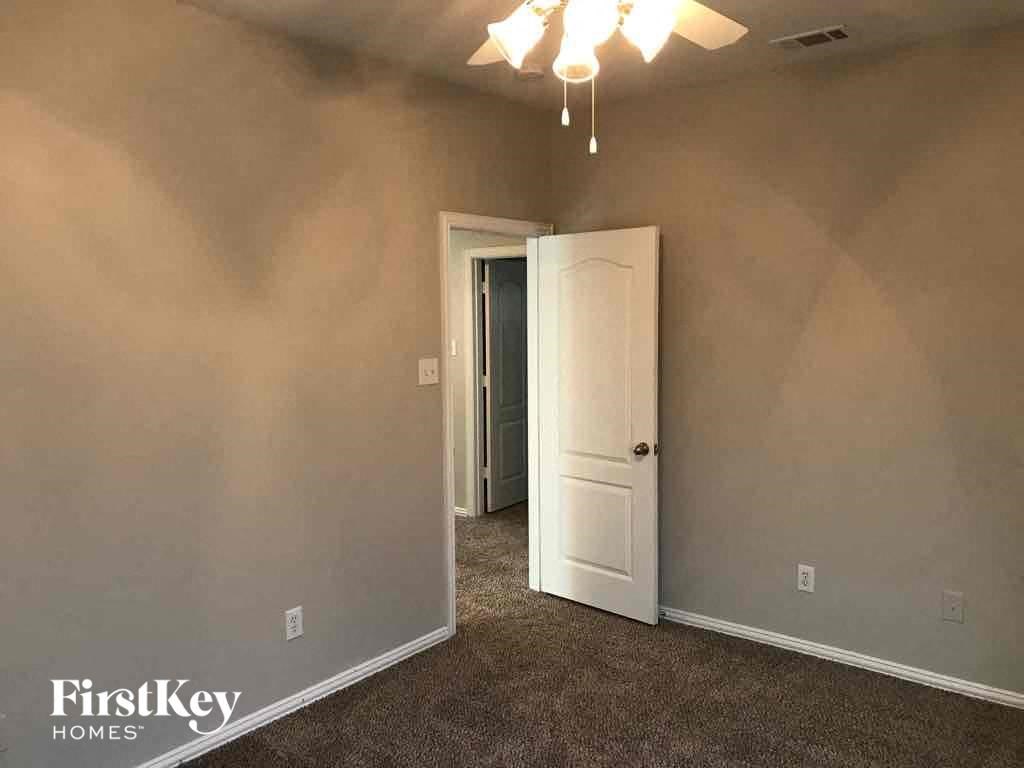 an empty living room with a white door and a ceiling fan