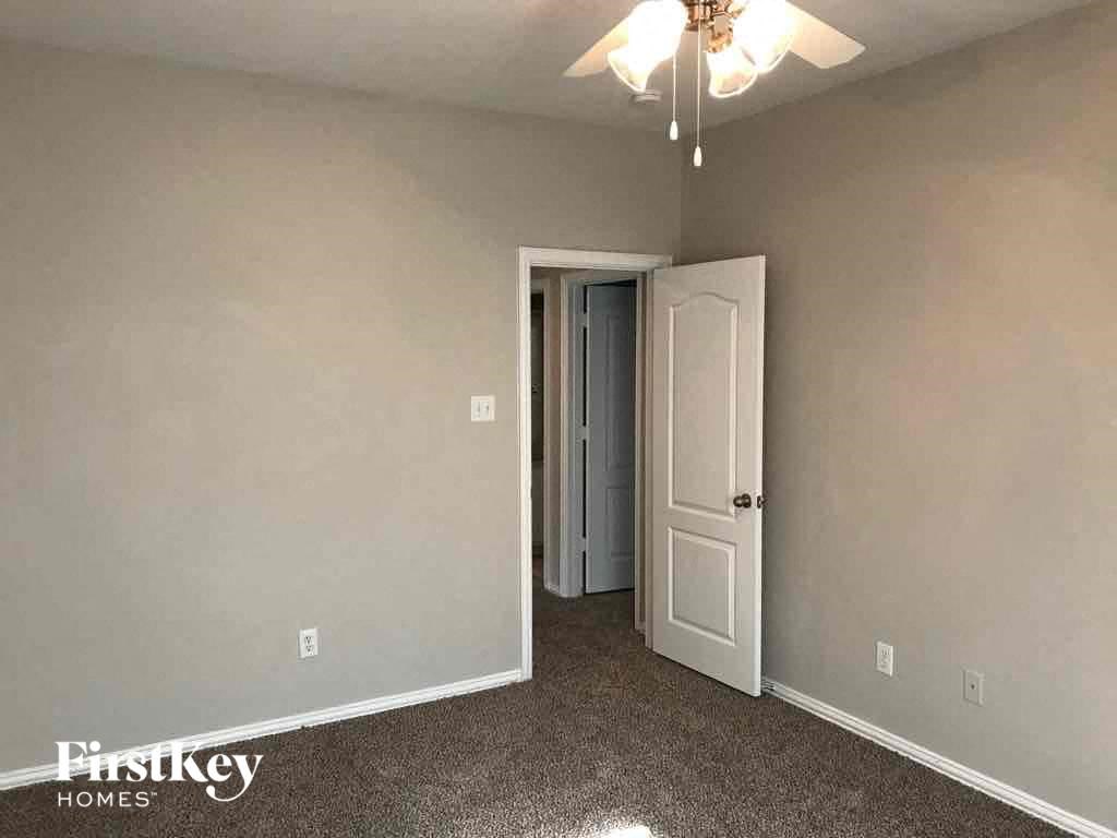 an empty bedroom with a white door and a ceiling fan