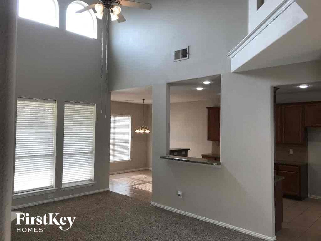 an empty living room with a ceiling fan and a window