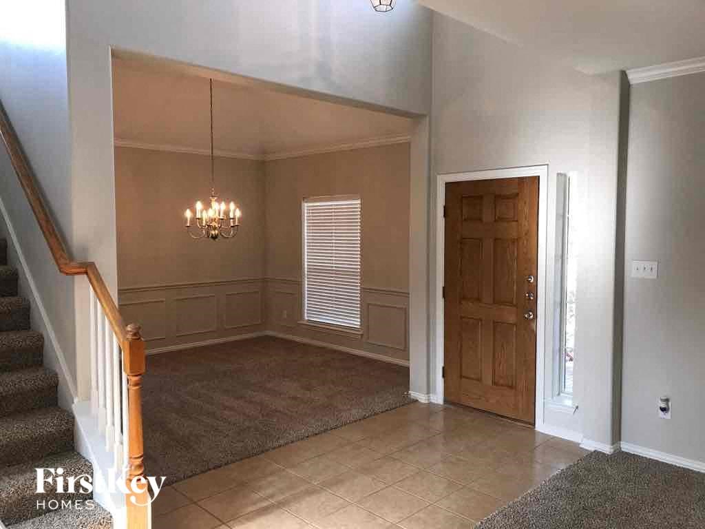 an empty living room with a wooden door and a chandelier