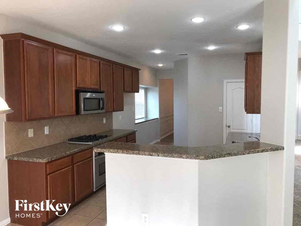 an empty kitchen with wooden cabinets and granite counter tops