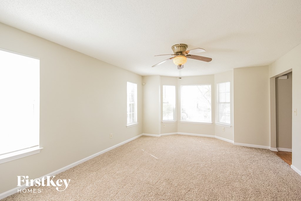 a spacious living room with carpet and a ceiling fan