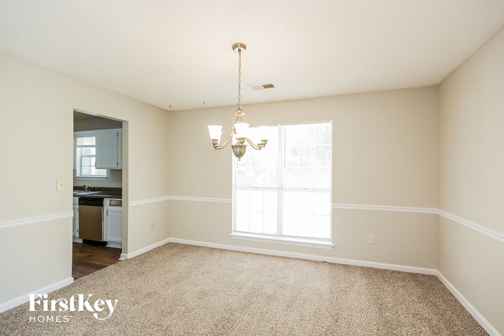 an empty living room with a chandelier and a window