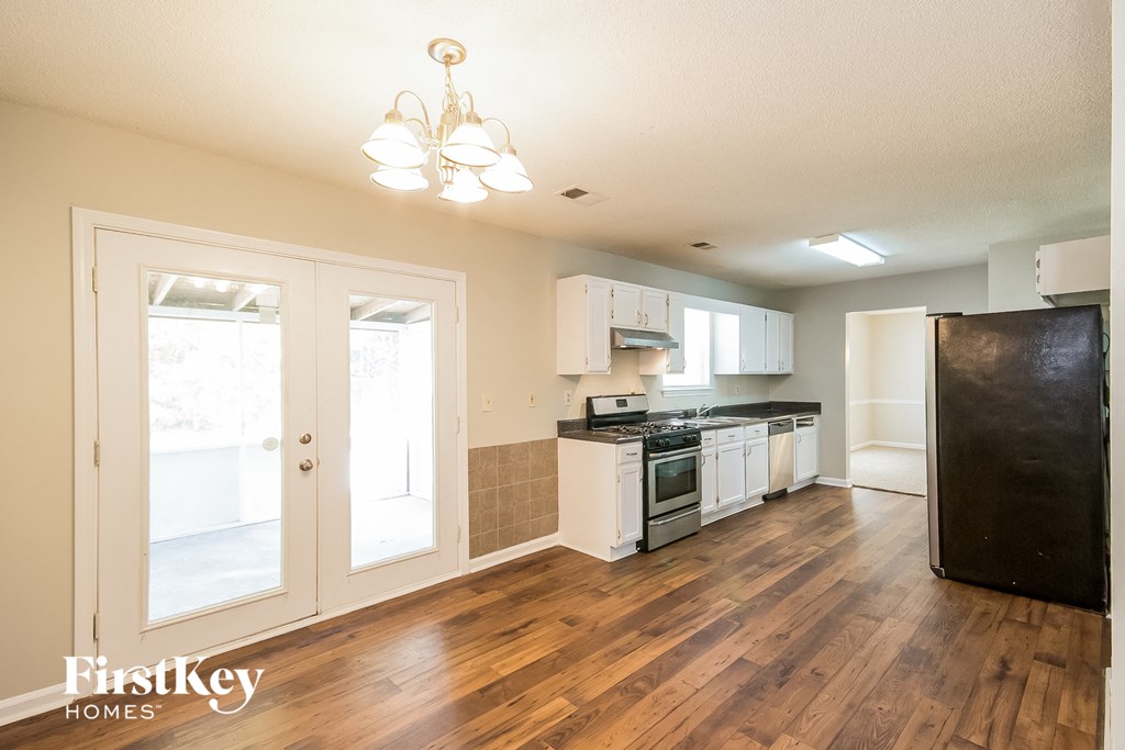 the kitchen and living room of a house with wood flooring and white cabinets