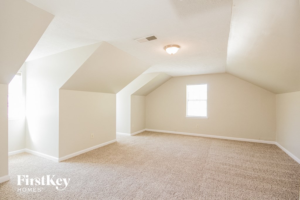 a white attic room with carpet and a window