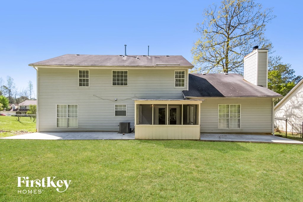 the back of a white house with a porch and a lawn