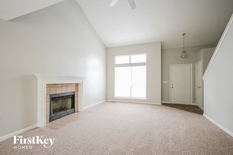A spacious room with a fireplace and a carpeted floor.
