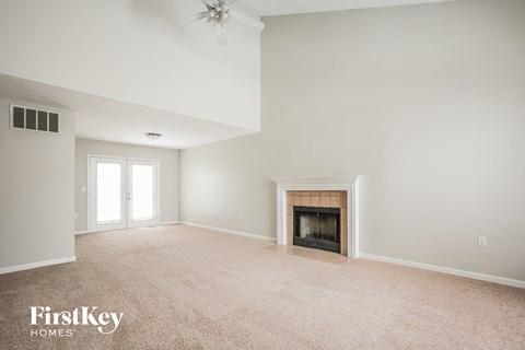 A spacious living room with a fireplace and a ceiling fan.