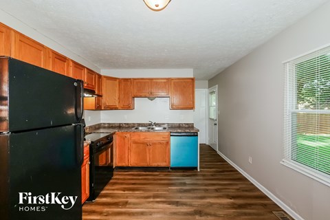A kitchen with wooden cabinets and a black fridge.