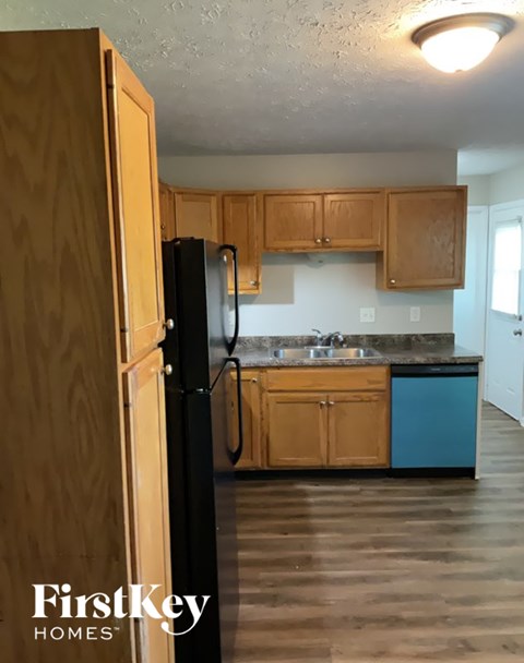 A kitchen with wooden cabinets and a black refrigerator.