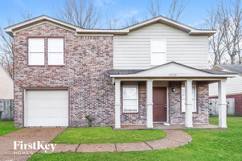 A brick house with a white garage door and a brown door.
