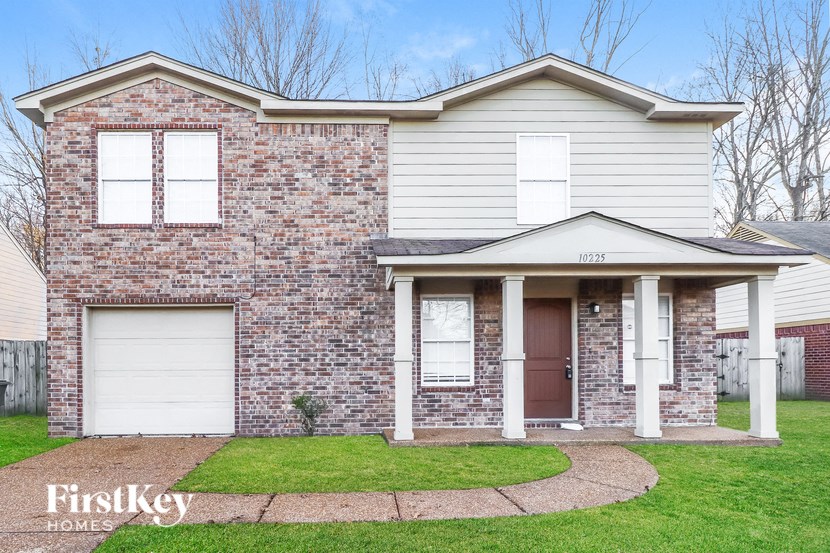 A brick house with a white garage door and a brown door.