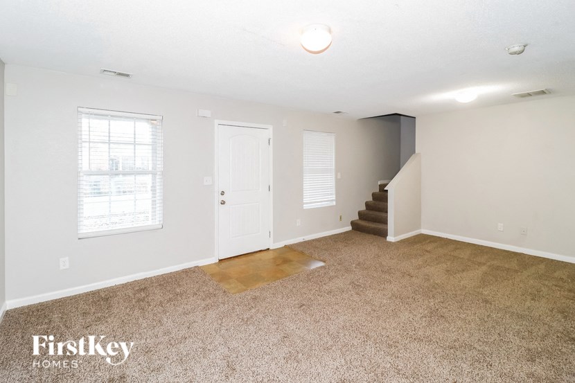 A room with a carpeted floor and a staircase leading to another room.