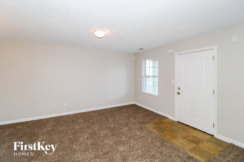 A room with a carpeted floor and a door on the right side.