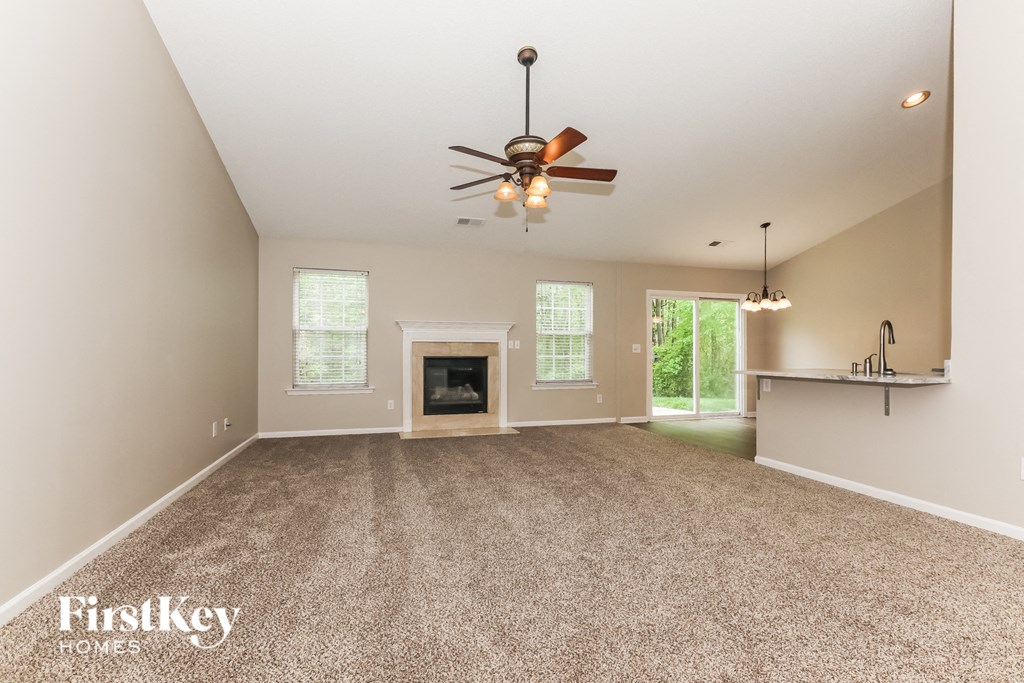 A spacious room with a fireplace and a ceiling fan.