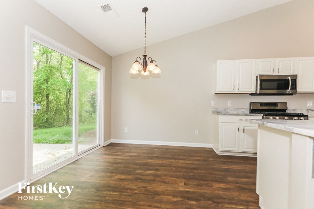 A kitchen with white cabinets and a wooden floor.