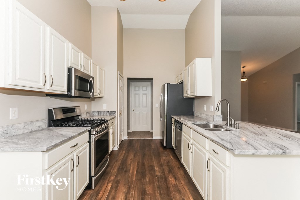 A kitchen with white cabinets and a marble counter top.