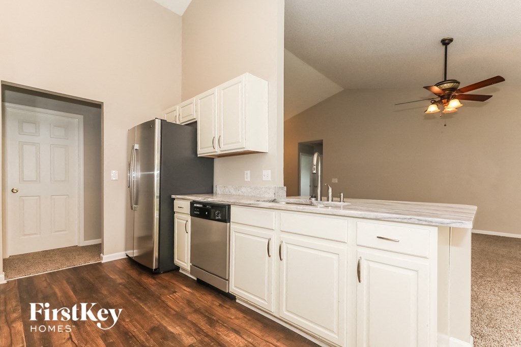 A kitchen with white cabinets and a stainless steel refrigerator.